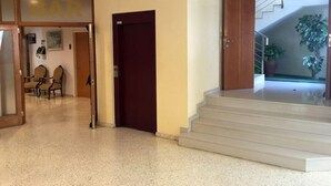 Vestíbulo de hotel con zona de bar, una escalera y un área de estar con sillas.