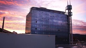 A modern building with a glass facade and a tall antenna structure. - MY Parkhotel by AR Hotels (Kempten)