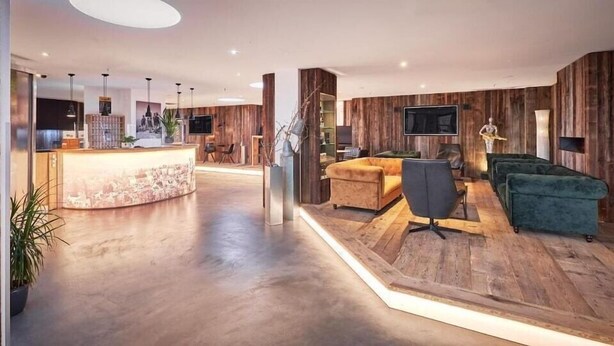 A modern interior with a reception desk, a sofa, and a television. - MY Parkhotel by AR Hotels (Kempten)
