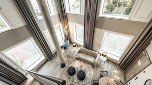 A high-ceiling room with large windows, a round coffee table, a sofa, and a dining table. - Harbr Hotel Konstanz (Konstanz)