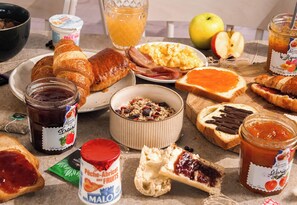 A breakfast table with croissants, ham, eggs, and various jams. - B&B Hotel Cergy Pierrelaye (Pierrelaye)