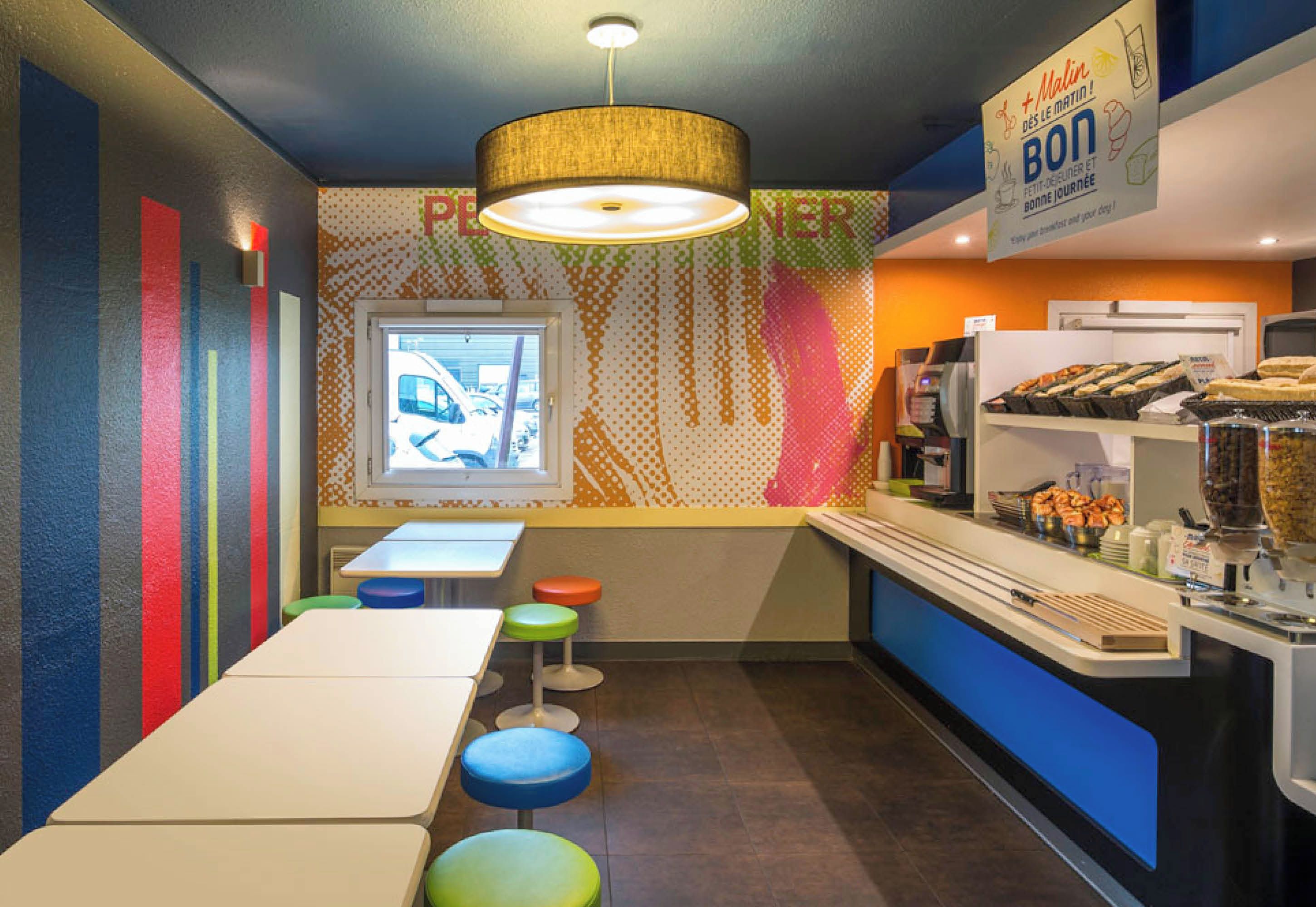 A restaurant with a counter, stools, and a window with a view.