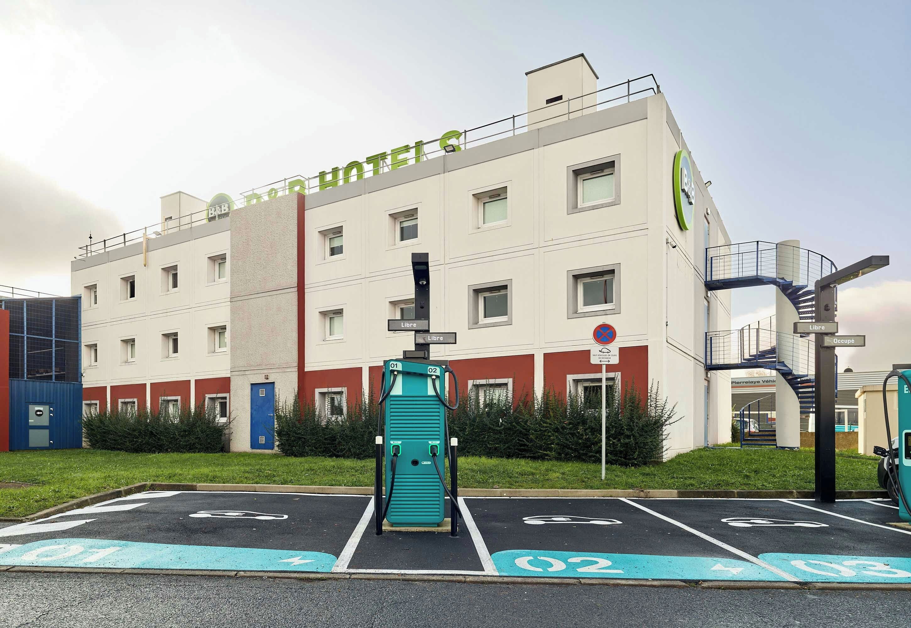 A hotel with a parking area marked with electric vehicle charging stations.
