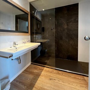 A modern bathroom with a glass shower enclosure, a white sink, and a wooden floor. - Hey Peniscola (Peniscola)