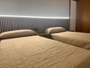 Ein Hotelzimmer mit zwei Betten, einem Schreibtisch und einer Wandleuchte.