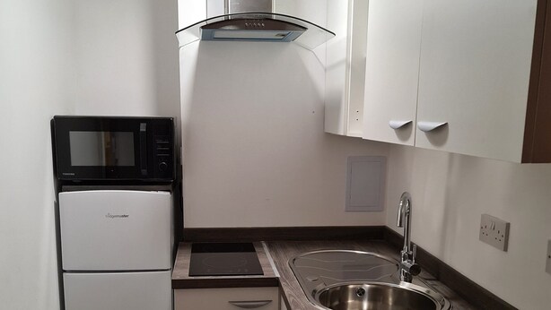 A compact kitchen with a microwave, refrigerator, stove, sink, and wooden countertop. - Kegworth Hotel & Conference Centre (Derby)