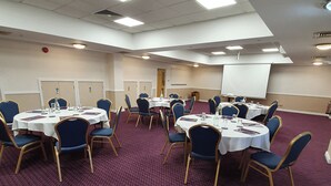 A conference room with round tables, blue chairs, and a whiteboard. - Kegworth Hotel & Conference Centre (Derby)