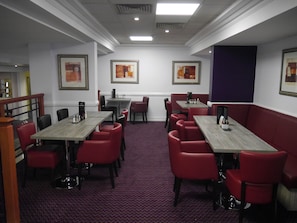 A restaurant with red upholstered booths, grey tables, and framed artwork on the walls. - Kegworth Hotel & Conference Centre (Derby)