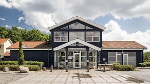 A two-story building with a reception area, numbered 19, and a tiled patio with potted plants. - Sleep2night (Helsingor)