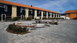 A courtyard with a fountain, benches, and a building with a tiled roof. - Sleep2night (Helsingor)