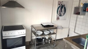A kitchen with a stove, oven, and a dish rack with plates and pots. - Sleep2night (Helsingor)