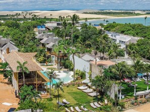 Un complexe hôtelier proposant plusieurs types d’hébergements en style bungalow, un espace piscine central et une vue sur la plage.