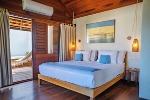 Une chambre avec un lit, une fenêtre avec des rideaux, un climatiseur fixé au mur et un tableau.