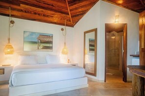 Un dormitorio con una cama grande, techo de madera, dos lámparas de pared, un cuadro y un espejo.