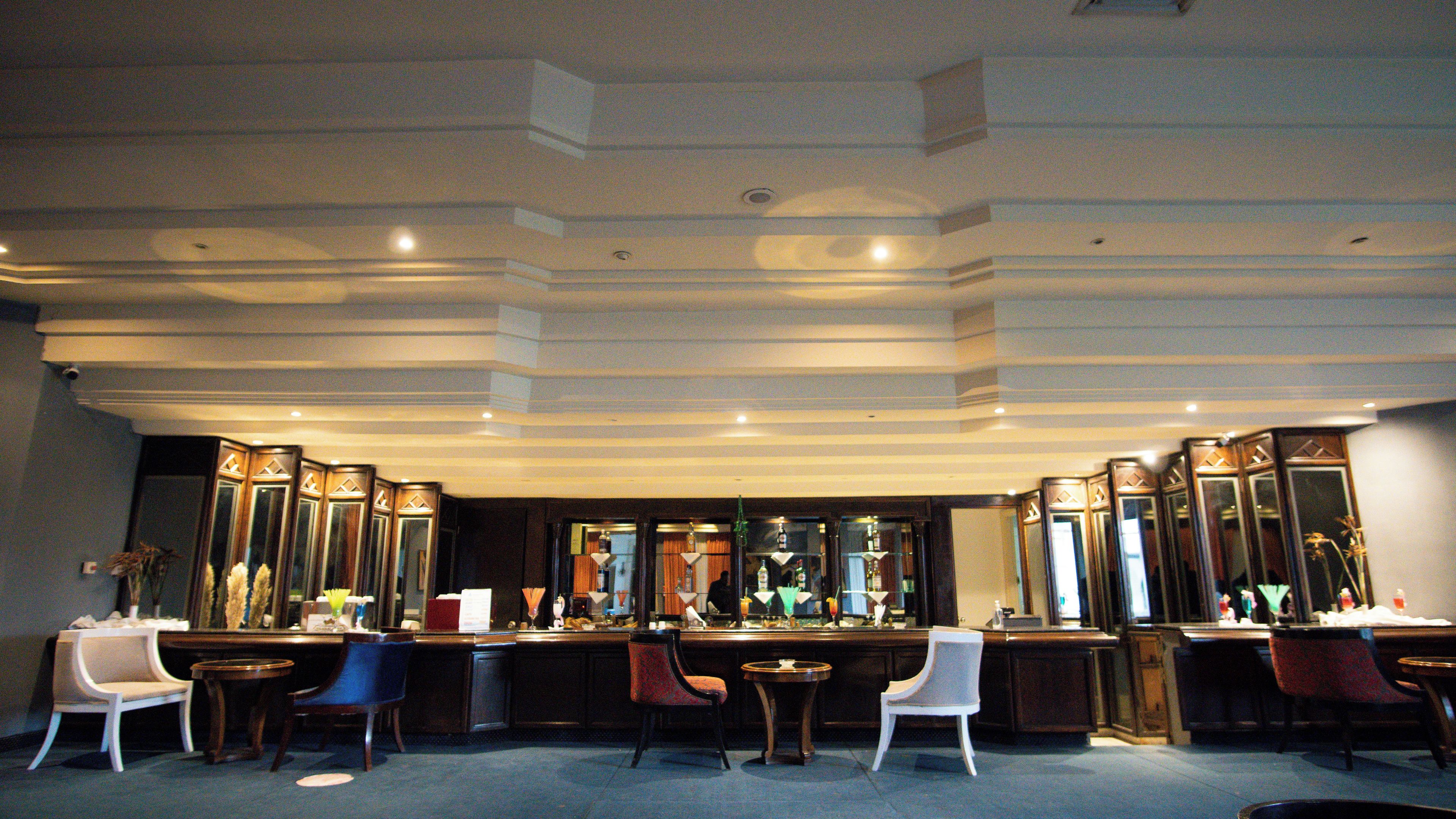 A hotel lobby with a reception desk, multiple chairs, and a large mirror.