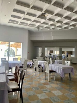 A spacious dining area with multiple tables and chairs, a tiled floor, and a high ceiling with a grid pattern. - Blumar Resort and Spa (Hammamet)