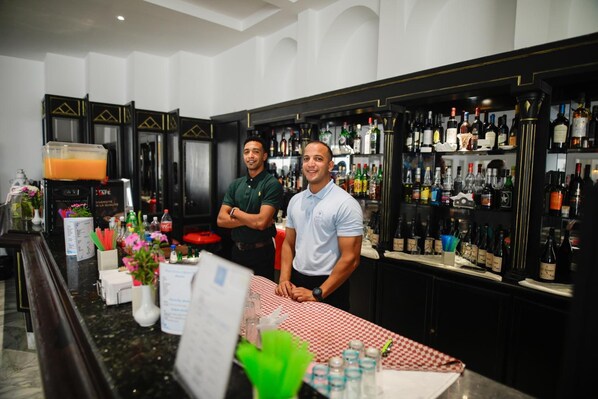 A bar area with a checkered tablecloth, a coffee machine, and a variety of bottles on shelves. - Blumar Resort and Spa (Hammamet)