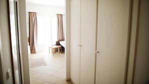 A hallway leading to a room with a large wardrobe, a dining area with a table and chairs, and a view of the outside through a window. - Blumar Resort and Spa (Hammamet)