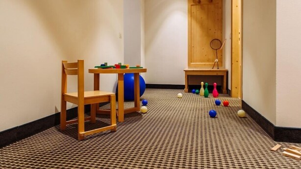 A small room with a wooden chair, a small table, a blue exercise ball, and a ping pong table. - Hotel Schloss Pontresina Family Spa (Pontresina)