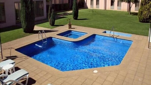 A rectangular swimming pool with a tiled deck, surrounded by lounge chairs and a well-maintained lawn. - Diego De Almagro Centro Los Angeles (Los Angeles)