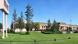 A building with a large sign, surrounded by trees and a well-maintained lawn. - Diego De Almagro Centro Los Angeles (Los Angeles)