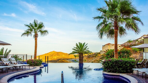 A pool area with lounge chairs, palm trees, and a mountain view. - Montecristo 3-bedroom house with AC , pool in Cabo San Lucas (Cabo San Lucas)