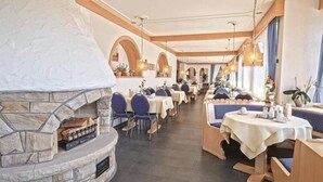 A restaurant with stone walls, blue upholstered booths, and a central fireplace. - Waldachtal Business Balance (Waldachtal)