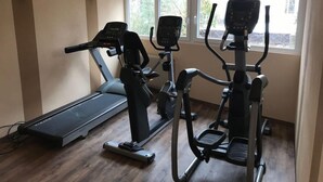 A home gym with a treadmill, elliptical, and stationary bike, large windows, and a wooden floor. - Waldachtal Business Balance (Waldachtal)