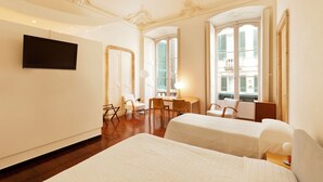 A hotel room with two beds, a desk, and a TV. - Locanda di Palazzo Cicala (Genoa)