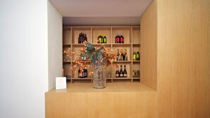 A wooden display with wine bottles and a vase with branches and flowers. - Locanda di Palazzo Cicala (Genoa)