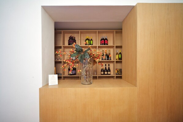 A wooden display with wine bottles and a vase with branches and flowers. - Locanda di Palazzo Cicala (Genoa)