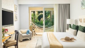A hotel room with a bed, a desk, a chair, a hammock, and a view of a lush garden through a sliding door. - Relax in Style at Luxury Beachfront Escape at Villa Del Palmer
5-Star Oceanfront (Cancún)