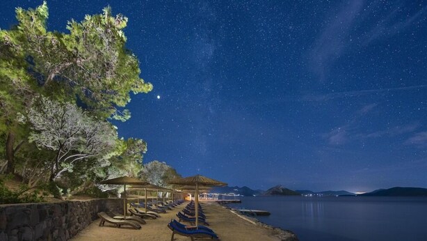 A beach with lounge chairs and umbrellas under a starry sky. - Lalibay Resort & Spa - Adults Only (Aegina)