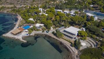 Vista aérea de una propiedad costera con piscina, varias edificaciones y una zona de playa.