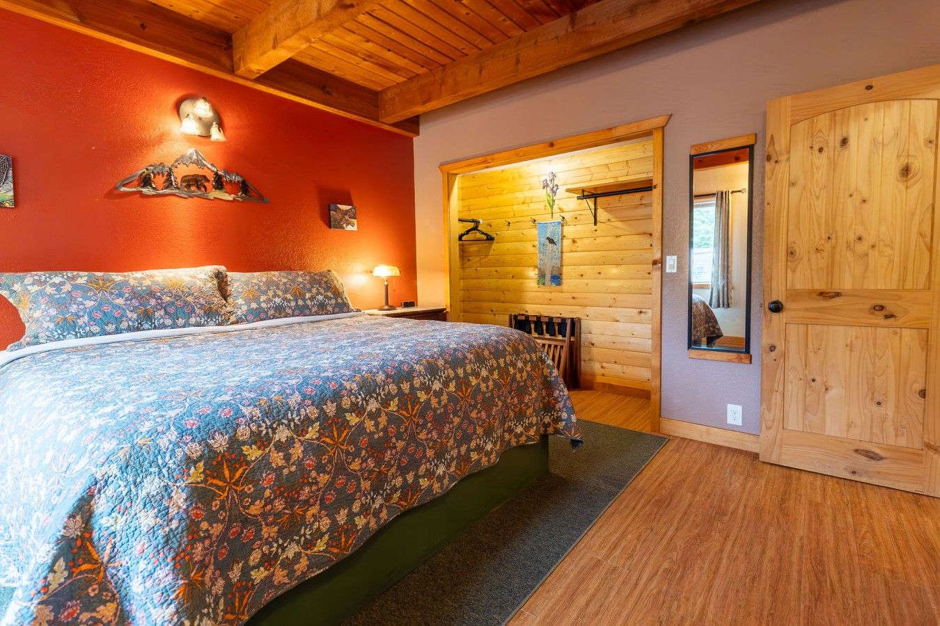 A bedroom with a bed, a wooden door, and a wall with a light fixture.