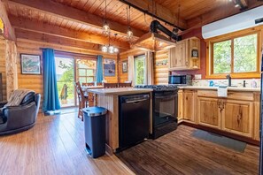 A cabin interior with a kitchen, dining area, and a seating area with a fireplace. - Alaska Lakeside Cottage (Seward)