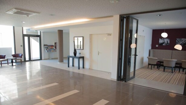 A spacious lobby with a modern design, featuring a reception desk, seating area, and a wall with framed artwork. - Résidence Nemea L'estacade (Capbreton)