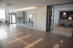 A spacious lobby with a modern design, featuring a reception desk, seating area, and a wall with framed artwork.
