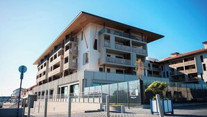 A multi-story building with balconies, a covered entrance, and a paved area in front. - Résidence Nemea L'estacade (Capbreton)