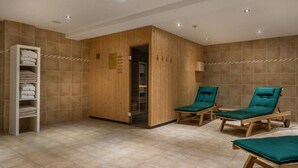 Een sauna met houten wanden, een handdoekhouder en twee groene fauteuils.