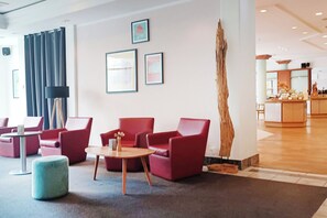 A lobby with red seating, a coffee table, and framed artwork on the wall. - Select Hotel Russelsheim (Ruesselsheim)