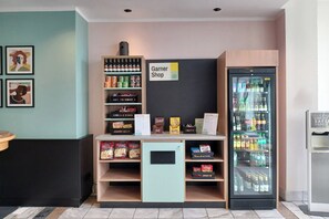 A snack bar with a cooler, a Garner Shop sign, and a hand sanitizer dispenser. - Select Hotel Russelsheim (Ruesselsheim)