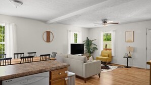 Ein geräumiger Wohnbereich mit Esstisch, Sofa und Deckenventilator.