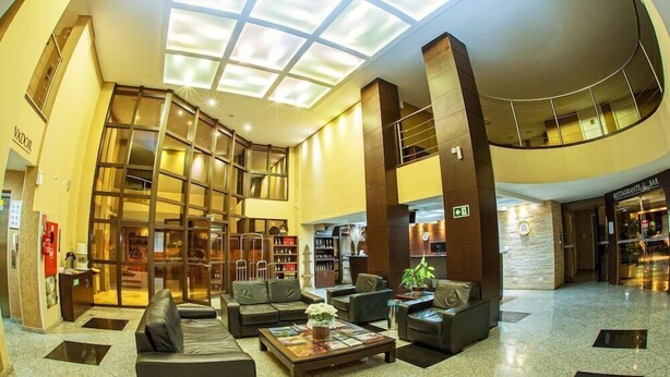A spacious lobby with a high ceiling, a central seating area, and a glass facade. - Hotel Campo Largo (Campo Largo)