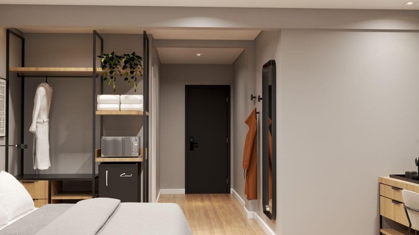 Quarto de hotel moderno com uma cama, escrivaninha, armário e porta para outro espaço.