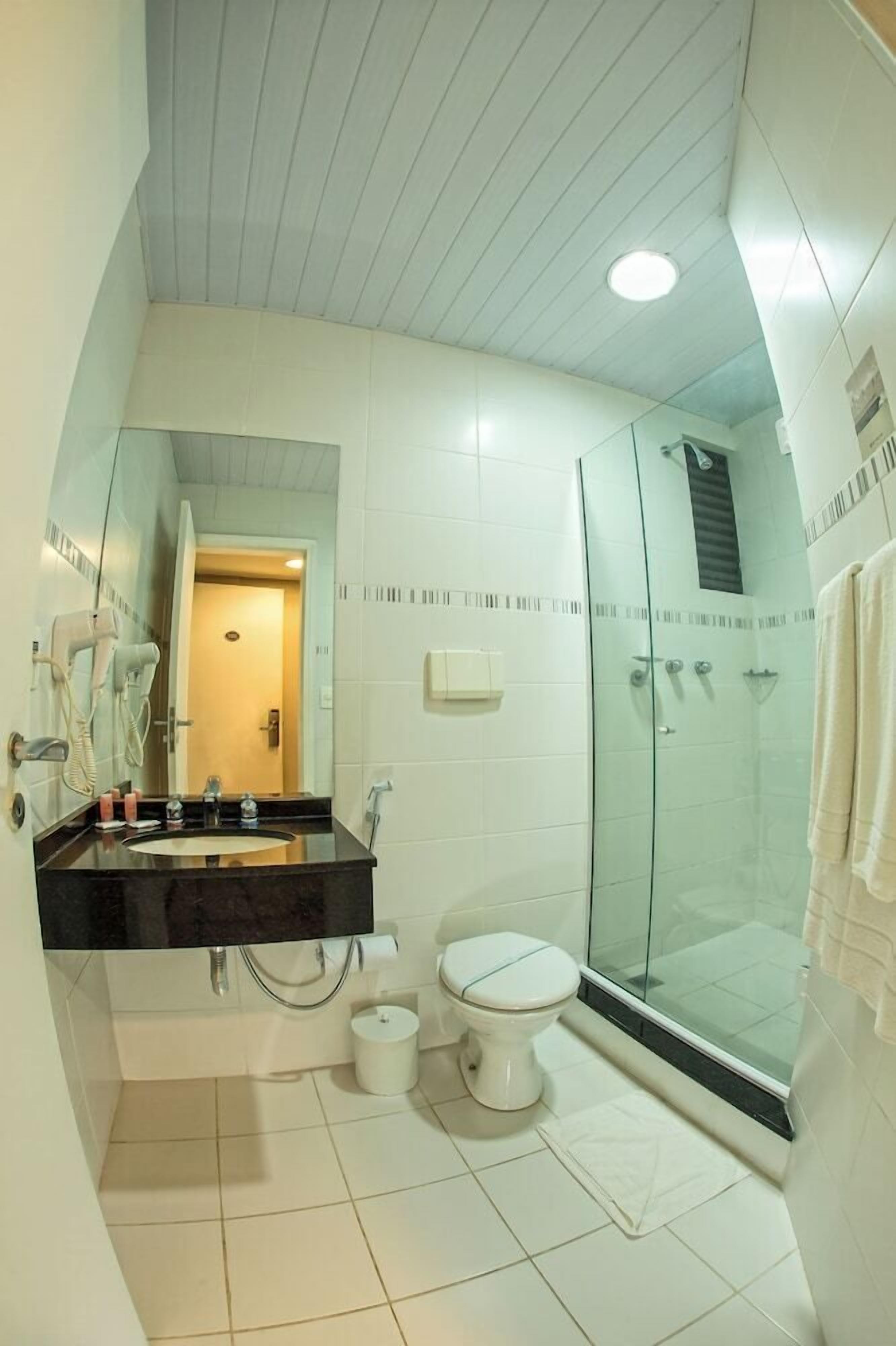 Un baño moderno con cabina de ducha de vidrio, inodoro blanco y tocador con espejo.