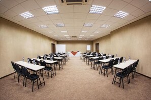 A conference room with multiple tables and chairs, arranged in rows facing a presentation screen. - Hotel Campo Largo (Campo Largo)