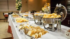 A buffet table with various food items, including bread and pastries, in a hotel setting. - Hotel Campo Largo (Campo Largo)