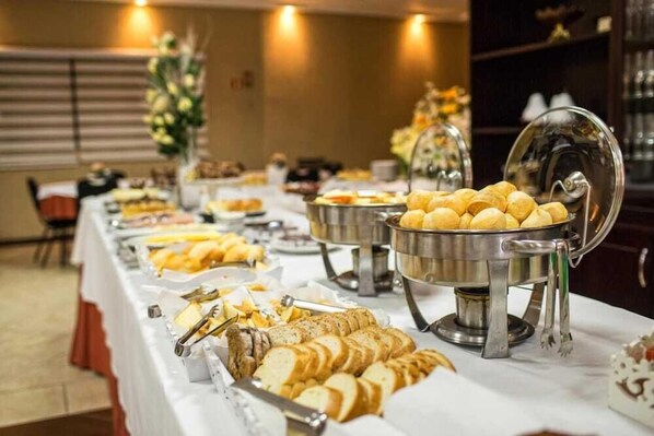 A buffet table with various food items, including bread and pastries, in a hotel setting. - Hotel Campo Largo (Campo Largo)