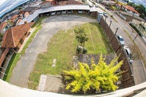 A parking lot with several cars, a grassy area, and a building with a curved roof. - Hotel Campo Largo (Campo Largo)